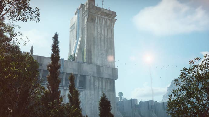 An ARC Raiders screenshot showing a large concrete tower beneath a bright blue sky. Mountains are visible in the background while thick green foliage can be seen in the foreground.